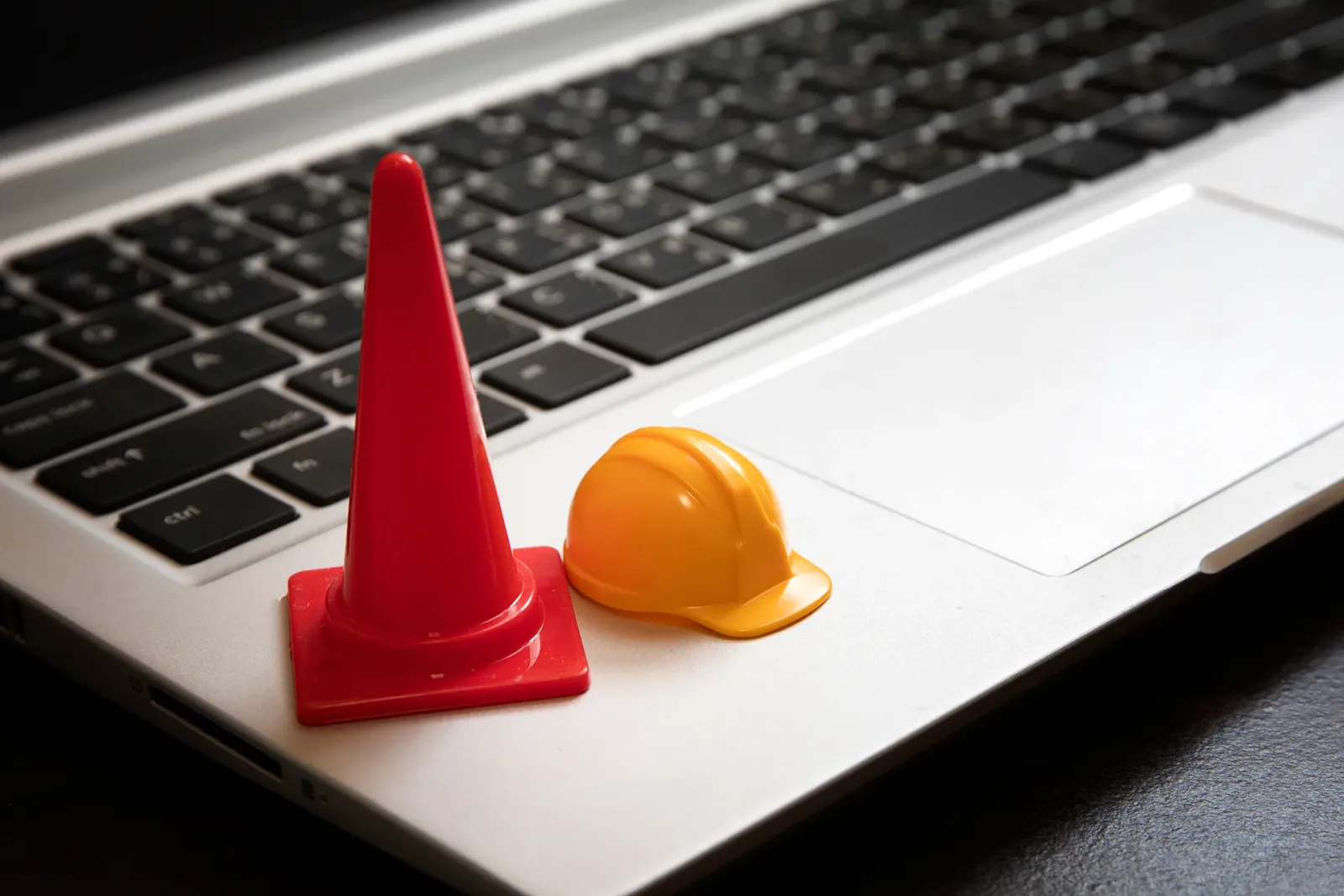 Miniature traffic cone and hard hat on a laptop keyboard, representing a smooth switch to a new internet provider